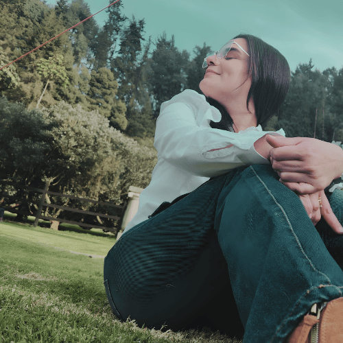 Daniela Fereira sentada en el césped al aire libre, conectando con la naturaleza y el bienestar digital consciente