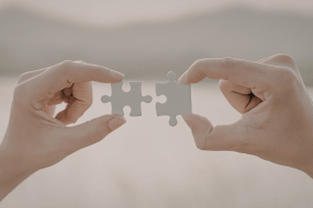 Manos uniendo piezas de rompecabezas, representando conexión, equilibrio y relación consciente con lo digital