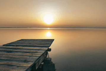 Muelle frente al agua al atardecer, representando calma, presencia y desconexión digital