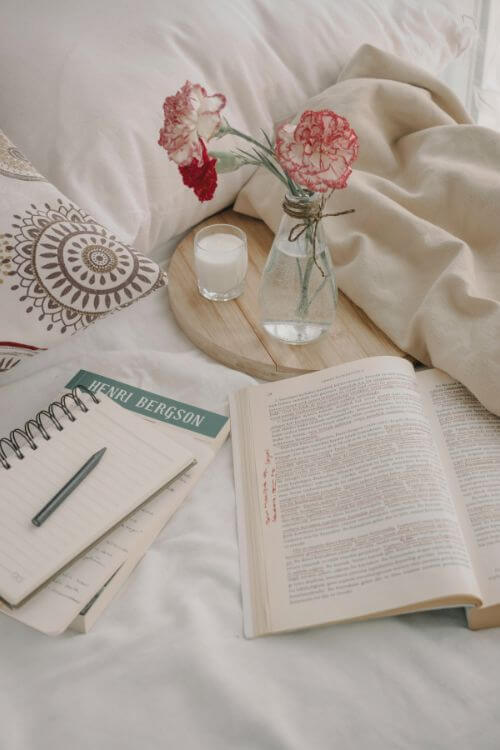 Libro abierto junto a libreta y flores en un espacio de lectura y escritura consciente.