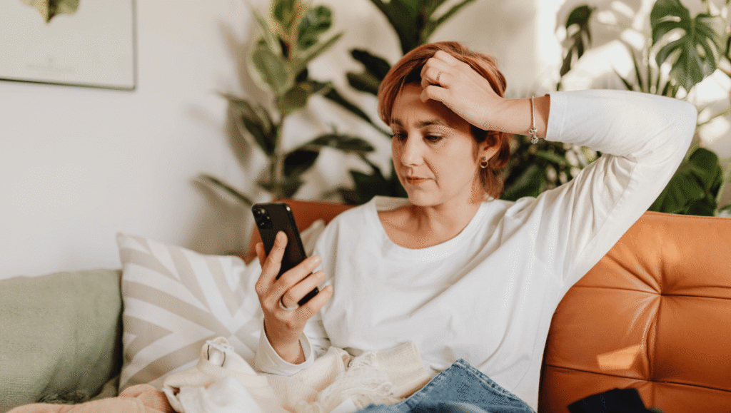 fatiga mental por sobreestimulación - mujer con el celular en la mano y la mirada perdida