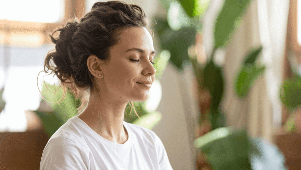 Mujer sentada en postura cómoda con los ojos cerrados realizando una pausa de respiración consciente.