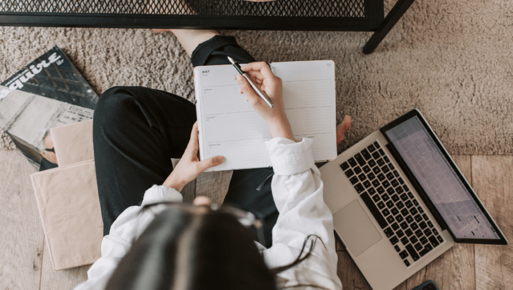 Mujer escribiendo en un cuaderno mientras reflexiona sobre su uso de redes sociales