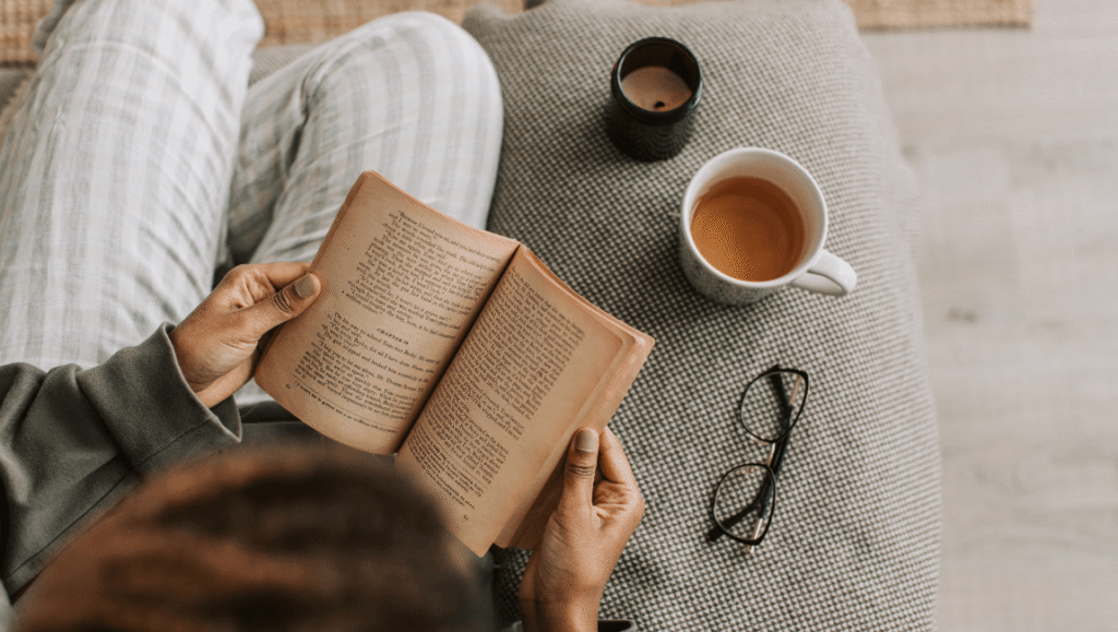 Persona en un espacio luminoso leyendo concentrada con una taza de una bebida caliente