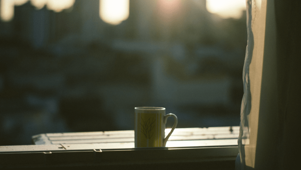 Taza sobre el borde de una ventana con luz cálida, un momento de pausa lejos del celular